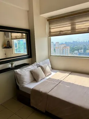 a bed in a room with a large window at NIJECRIFIL Condotel in Manila