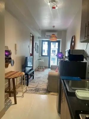 a kitchen and living room with a couch and a table at cozy 1 bedroom retreat Walk to Moa in Manila
