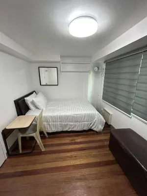 a bedroom with a bed and a table and a window at Simple but cozy, feel at home in Manila