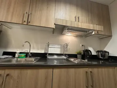a kitchen with a sink and wooden cabinets at Seaside Manila Bay Sunset View at SM Mall of Asia in Manila