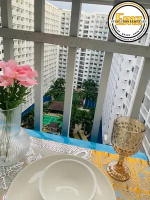 a table with a plate and a vase with flowers on a balcony at EMZ Shore Staycation 38 in Manila