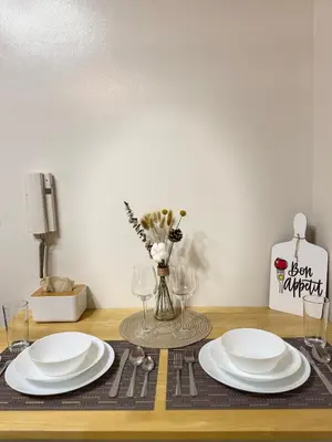 a table with two white plates and a vase with flowers at The Scandi Hub at Air Residences, Makati in Manila