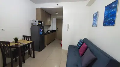 a living room with a blue couch and a kitchen at Shore Residences - 1BR Breezy Home Near the Sea in Manila
