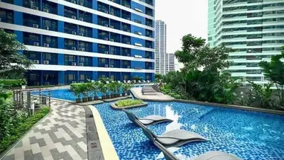 a large swimming pool with chairs and a building at Iris Affordable and Neat Staycation at Air Residences Makati in Manila