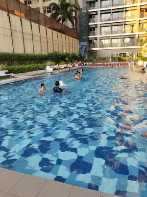 a group of people swimming in a large swimming pool at Chino Roces Makati - No Parking - Red Residences in Manila