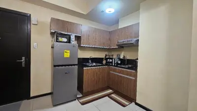 a kitchen with a refrigerator and wooden cabinets at The Radiance Manila Bay by SonPai in Manila