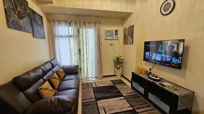 a living room with a couch and a flat screen tv at The Radiance Manila Bay by SonPai in Manila