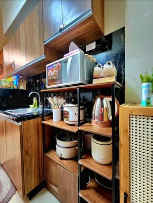a kitchen with wooden cabinets and a microwave on a shelf at Avida Towers Sucat in Manila