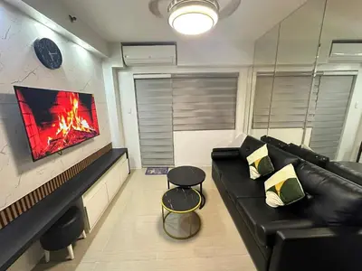 a living room with a black couch and a fireplace at Family room Staycation Near MOA in Manila