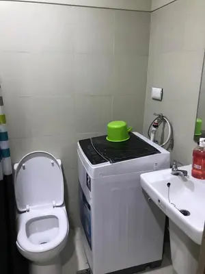 a bathroom with a toilet and a green bowl on a counter at 1 bedroom condo unit near MOA in Manila
