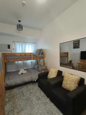 a bedroom with a bunk bed and a couch at Green 2 Residences Tower1 unit 512 in Dasmariñas