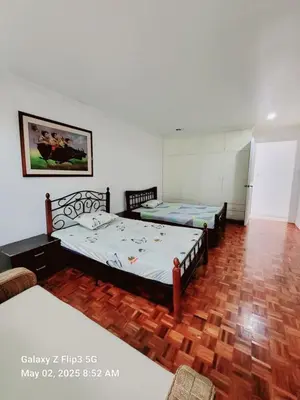 two beds in a room with a wooden floor at Majesty Suites in Manila