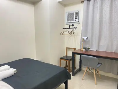 a bedroom with a bed and a desk and a window at Cozy Room in Modern Paraaque Condo with 2 Bedrooms in Manila
