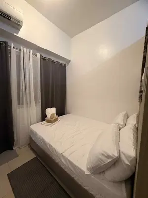 a small bedroom with a bed with white sheets at Shore Residences 1BR Staycation in Manila