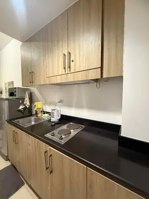 a kitchen with a sink and wooden cabinets at Shore Residences 1BR Staycation in Manila