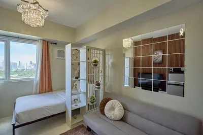a bedroom with a bed and a window and a chandelier at Vista Blooms Stay at Vista Shaw with WiFi in Manila