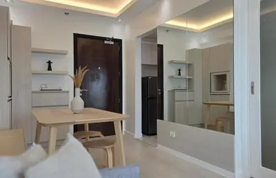 a living room with a table and a kitchen at Center of BGC- Your Home In Forbeswood Parklane in Manila