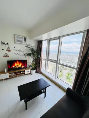a living room with a fireplace and a couch at Alex Staycation Home in BGC in Manila