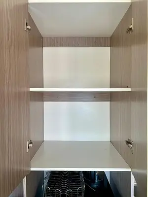 a kitchen with wooden cabinets with white shelves at The View Studio in Urban Deca Tower EDSA in Manila