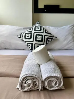 a pile of towels on a bed with a candle at The View Studio in Urban Deca Tower EDSA in Manila