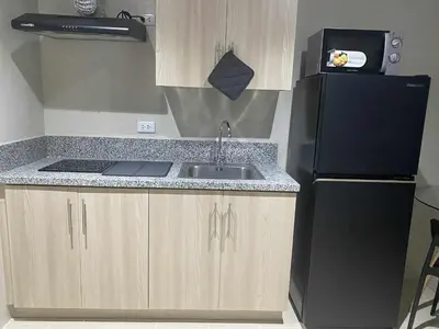 a kitchen with a sink and a black refrigerator at Kasara Urban Residences in Pasig City - Solmera Cove in Manila