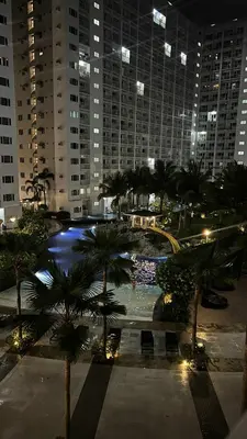 a large pool with palm trees in a city at night at Family Room Staycation Shore Residences Near Mall of Asia and Airport Adjacent Units - Perfect for Groups in Manila