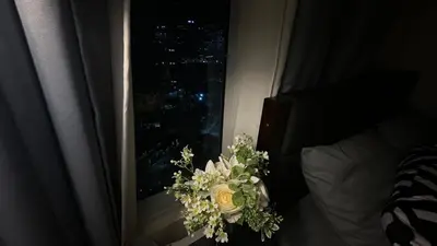 a bouquet of flowers in front of a window at Classy BGC Condo City View Pool Gym Sauna in Manila