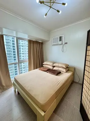 a bedroom with a large bed with a large window at Cozy Spacious BGC Condo near SM Aura, High Street in Manila