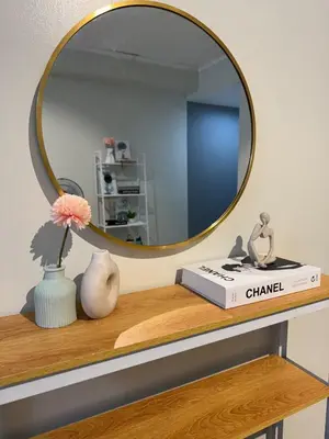 a mirror on top of a wooden shelf with a book at Cozy Spacious BGC Condo near SM Aura, High Street in Manila