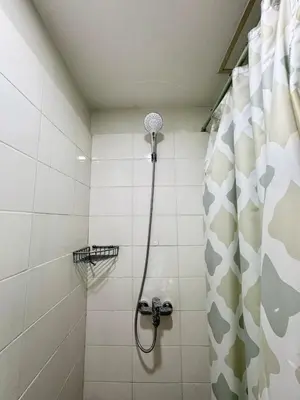a bathroom with a shower with a shower head at Cozy Spacious BGC Condo near SM Aura, High Street in Manila