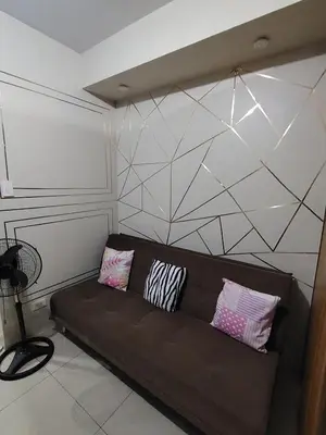 a brown couch with pillows on it in a room at Shell residences Near Moa Japs staycation in Manila