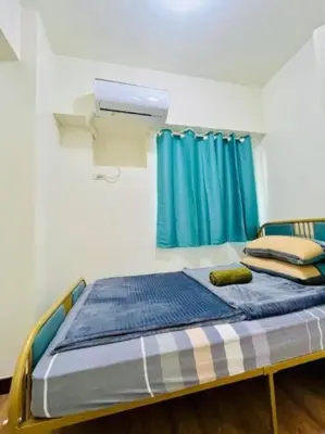 a bed in a room with a blue curtain at Vtan Condo FAIRLANE PASIG in Manila