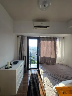 a bedroom with a bed and a dresser and a window at Air Residences Makati in Manila