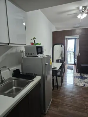 a kitchen with a sink and a microwave on top of a refrigerator at Air Residences Makati in Manila