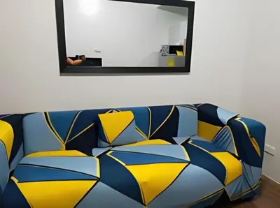 a blue and yellow couch in a room with a mirror at Makati Staycation at Air Residences in Manila