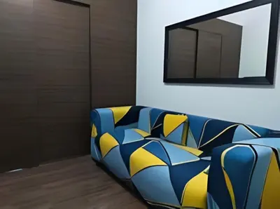 a blue and yellow couch in a room with a mirror at Makati Staycation at Air Residences in Manila