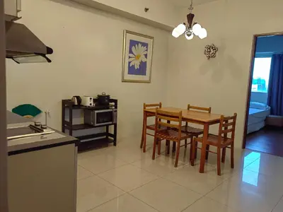 a kitchen and dining room with a table and chairs at Apartment in Rhapsody 2BR in Manila