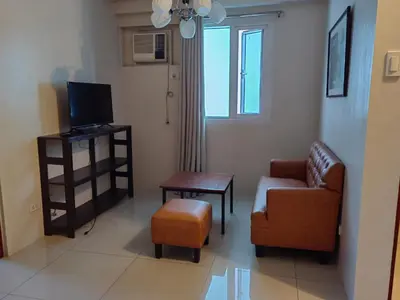 a living room with a couch and a chair and a television at Apartment in Rhapsody 2BR in Manila