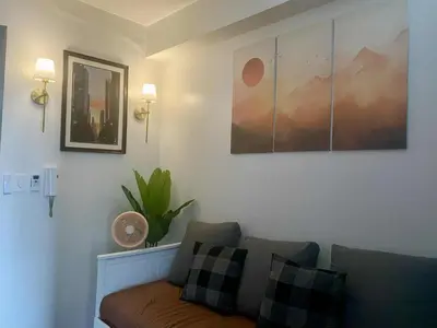 a living room with a couch and pictures on the wall at SOLACE by Athena at Air Residences Makati in Manila