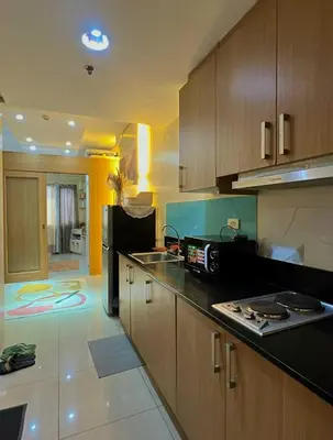 a kitchen with wooden cabinets and a black counter top at MOA Shell Residences Staycation in Manila