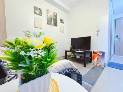 a living room with yellow flowers and a tv at SHORE 2 TOWER 2 NEAR MOA 16TH Floor in Manila