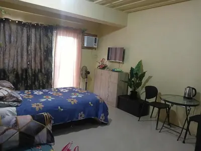 a bedroom with a bed and a table and a window at Deviente's Guesthouse in Manila