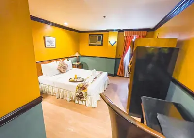 a room with a bed in a room with yellow walls at Miramar Hotel in Manila