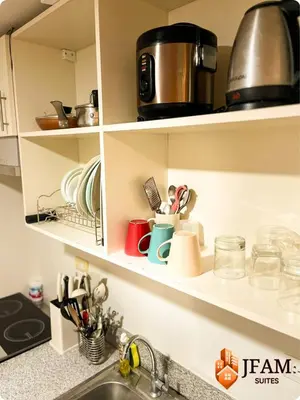 a kitchen shelf with dishes and utensils on it at JFam Suites, C3-9D Studio, Up To 4 Pax in Biñan