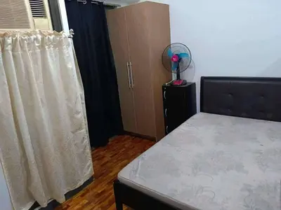 a bedroom with a bed and a window with a fan at The orienthal place, Makati a1 in Manila