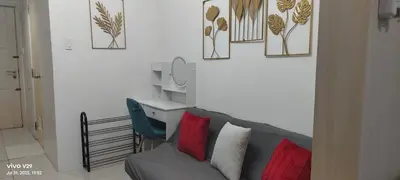 a living room with a gray couch and a mirror at Sea Residences Crisha in Manila