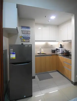 a kitchen with a refrigerator and wooden cabinets at Kuya Awens Staycation in Manila