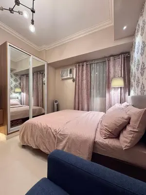 a bedroom with a large bed and a mirror at Charming Unit at Smdc Sun Residences in Manila