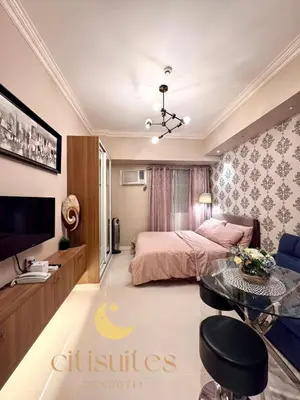 a bedroom with a bed and a table and a tv at Charming Unit at Smdc Sun Residences in Manila