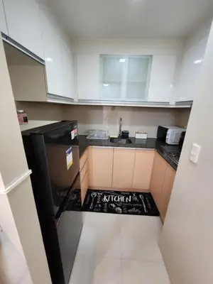 a small kitchen with white cabinets and a black appliance at Cozy Condo Unit Near NAIA Terminal 3 in Manila